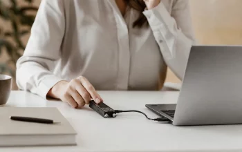 Digital voice recorder connected to a laptop with USB cable on a clean desk